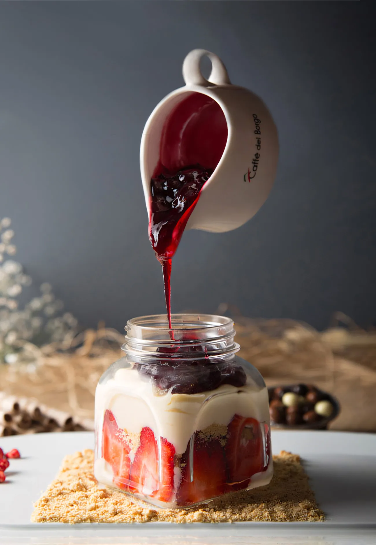 Proje: Cafe del Borgo Kavanozda çilekli magnolia tatlısı üzerine soslukla frambuaz sos dökülüyor.