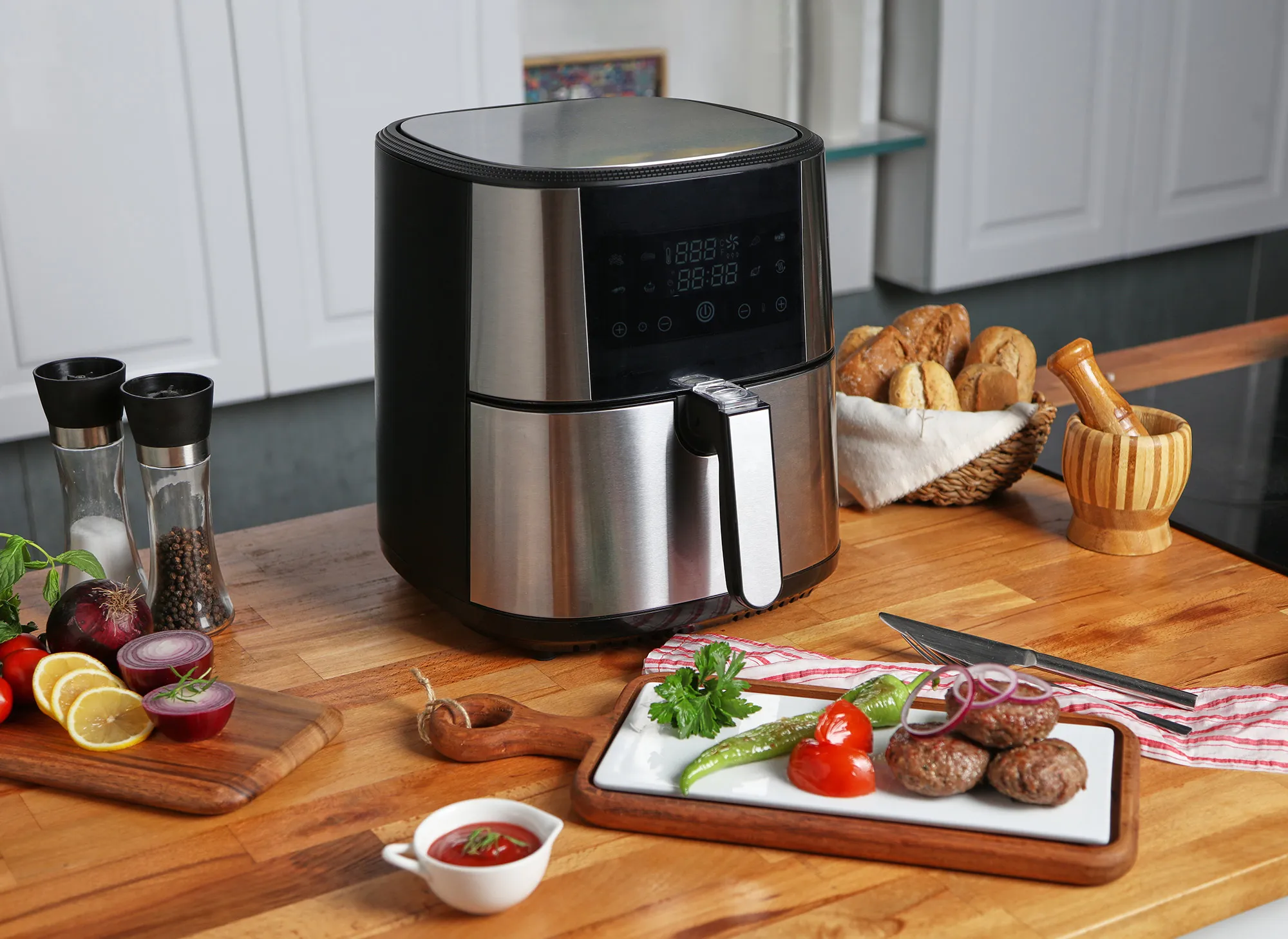 Proje: Fabcio Airfryer - Ajans: Dijifabrik - Yemek Stilisti: Şükran Kayaoğlu Ahşap masa üstünde pişirme makinesi ve önünde kızarmış köfteler.