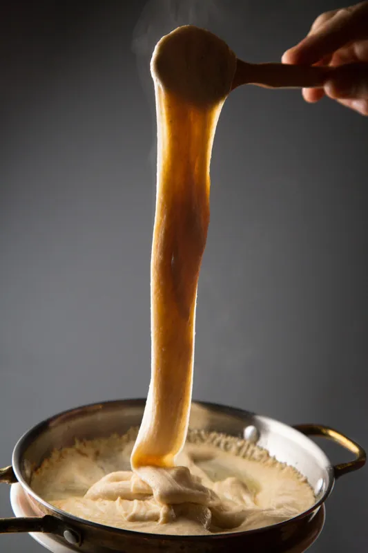 Proje: Cafe del Borgo Ahşap kaşık ile yukarı doğru uzatılan muhlama görüntüsü üzerinden dumanları tütüyor.