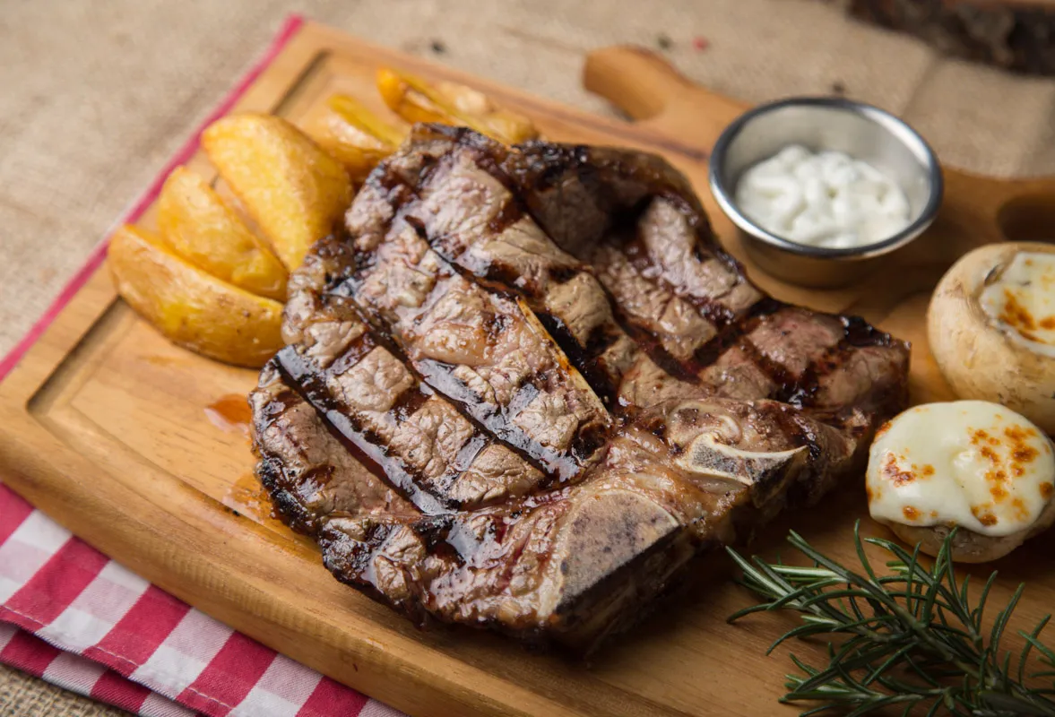 Proje: Cafe del Borgo Üstten görünüş büyük bir biftek, üzerinde ızgara izleri var.
